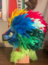 a colorful feathered mask on a mannequin