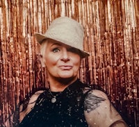 a woman wearing a hat in front of a gold backdrop