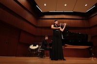 a woman in a black dress is playing a violin
