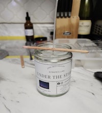 a jar of a candle with a wooden stick in it