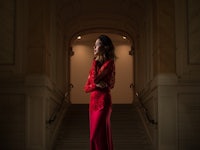 a woman in a red dress standing on a staircase