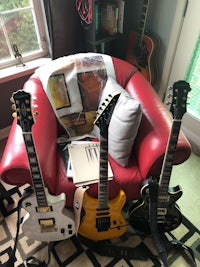 three guitars sitting on a red chair