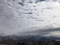 a cloudy sky with mountains in the background