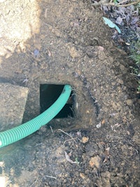 a green hose is attached to a hole in the ground