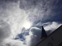 the sun shines through the clouds above a church steeple