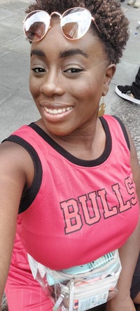 a woman in a pink shirt and sunglasses is posing for a photo