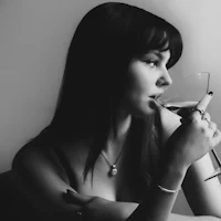 a black and white photo of a woman drinking wine