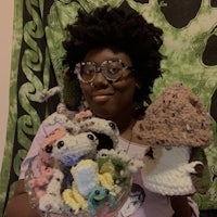 a woman holding a bowl of crocheted hats