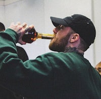 a man with tattoos drinking from a bottle