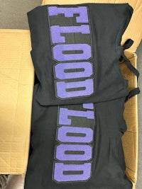 two black and purple t - shirts in a box