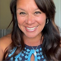 a woman smiles while wearing a blue top