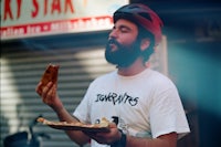 a man wearing a helmet holding a piece of pizza