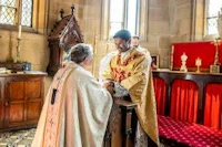 a priest is shaking hands with another person in a church
