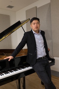a man leaning against a black grand piano