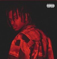 a man with dreadlocks standing in front of a red background