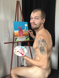 a naked man painting on an easel