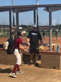 a young girl is talking to a coach on a softball field