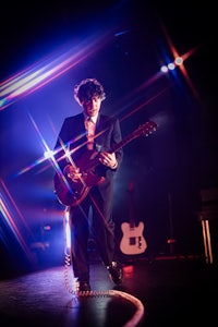 a man in a suit playing a guitar on a stage