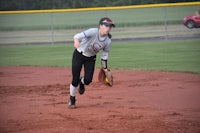 a female softball player is running to catch a ball