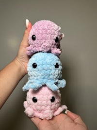 a person holding a blue octopus plush toy in front of a brick wall