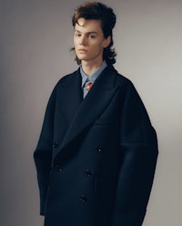 a man in a black coat and tie posing for a photo