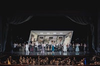 a group of people standing on stage in front of a large screen