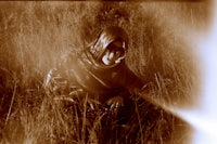 a woman sitting in a field with a laptop