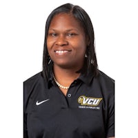 a woman in a black polo smiles for the camera
