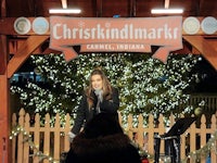 a woman singing in front of a christmas tree