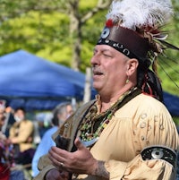 a man in a feathered headdress is speaking to the crowd