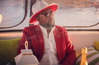 a man in a red jacket and hat sitting on a boat