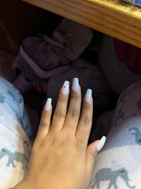 a woman's hand with a white nail polish on it