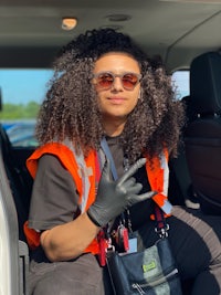 a woman with curly hair sitting in the back seat of a car