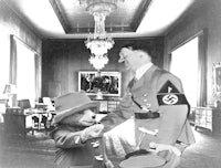 a man in uniform shaking hands with a teddy bear