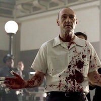 a man with blood on his hands is standing in a room