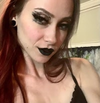 a woman with long red hair and black lipstick