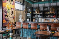the interior of a restaurant with a mural on the wall