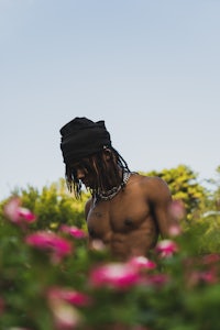 a man in a hat standing in a field of flowers