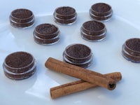 five small jars of cocoa powder and cinnamon sticks on a plate