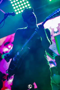 a man playing a guitar in front of colorful lights