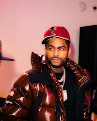 a man in a jacket and hat standing next to another man