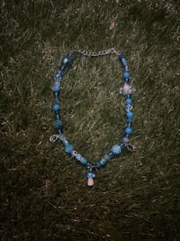 a necklace with blue beads laying on the grass