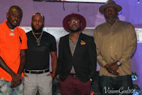four men posing for a picture in front of a television