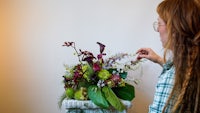 a woman is arranging flowers in a wicker basket