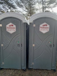 two portable toilets in a wooded area