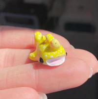 a person holding a small yellow fish figurine
