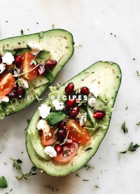 two avocados with tomatoes and pomegranate on top