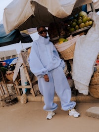 a man in a blue sweatsuit standing in front of a market