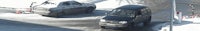 two cars are parked on a snowy road