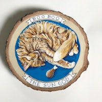 a wooden slice with an image of a cat laying on it